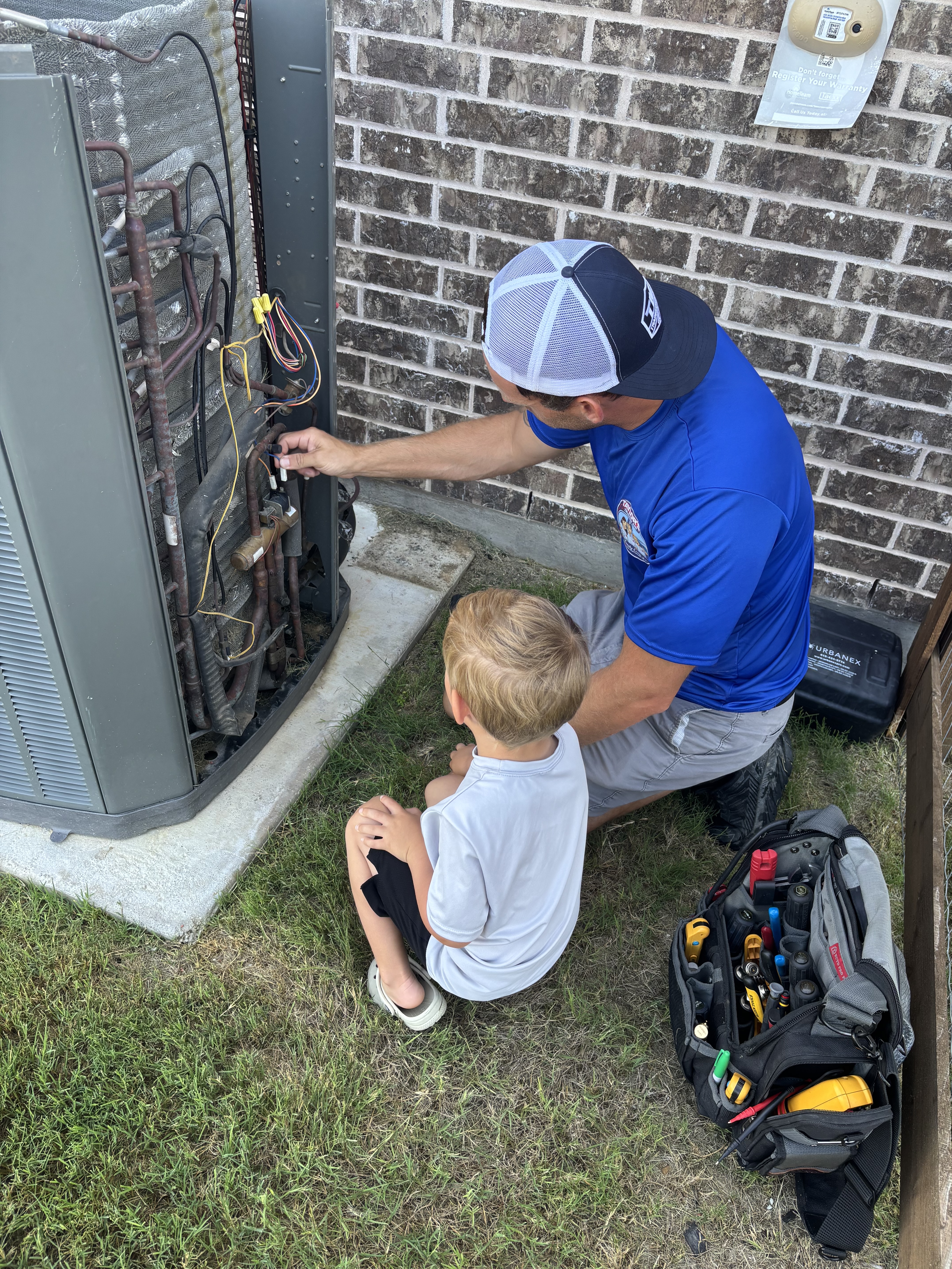 Taylor and son working on an outdoor AC unit